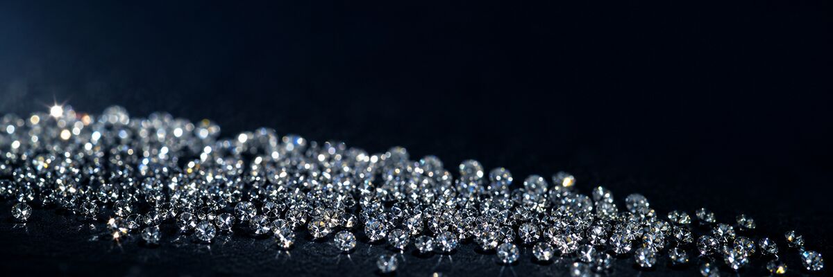 A drift of several hundred natural round brilliant cut melee diamonds catching light across a dark surface